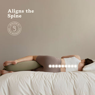 Person lying on a bed with a bbhugme pregnancy pillow under their head, aligning the spine.